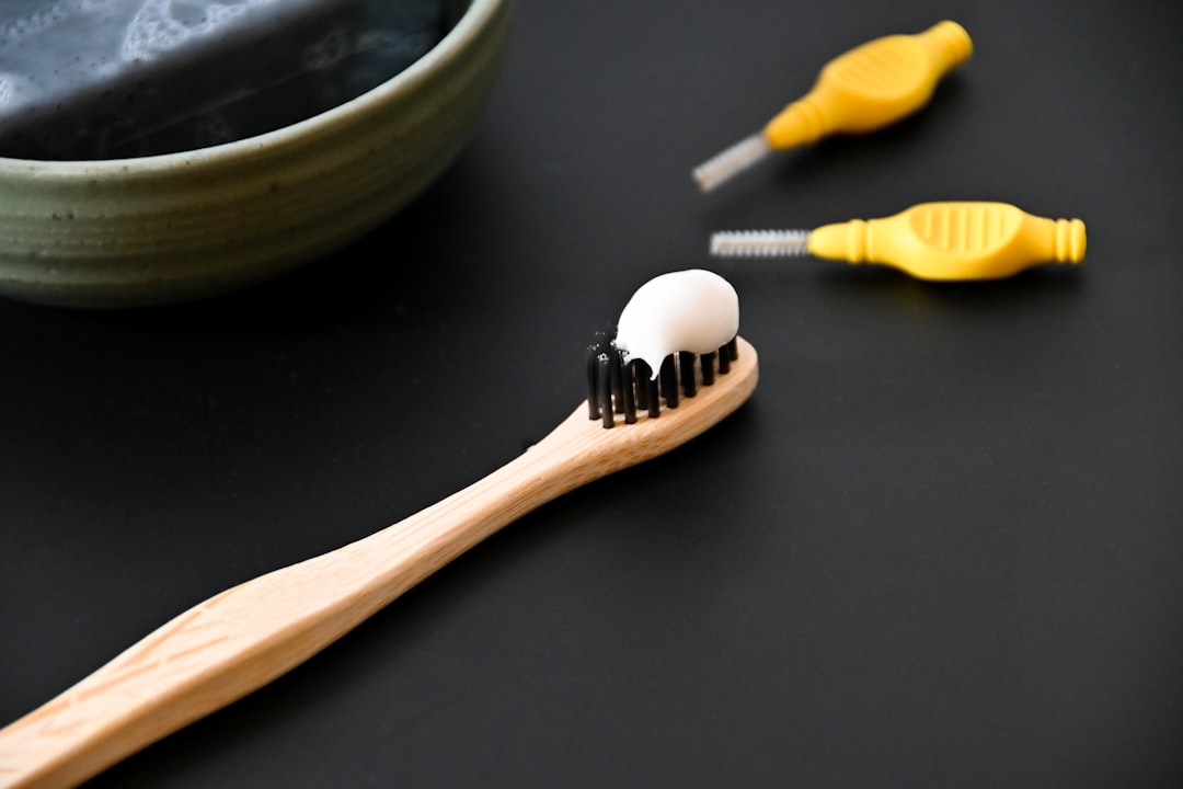 a-toothbrush-with-a-toothpaste-on-it-next-to-a-bowl-of-tooth-nj0egjdv6ng